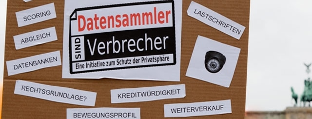 Demo-Plakat vor dem Brandenburger Tor mit dem Spruch „Datensammler sind Verbrecher“