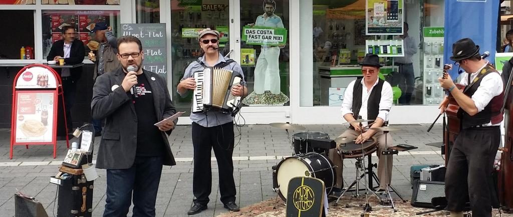 Stefan Borggraefe mit Straßenmusikern der Band Musik for the Kitchen auf dem Berliner Platz