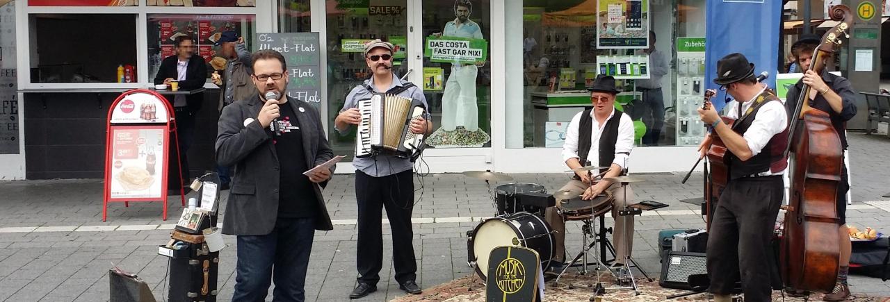 Stefan Borggraefe mit Straßenmusikern der Band Musik for the Kitchen auf dem Berliner Platz